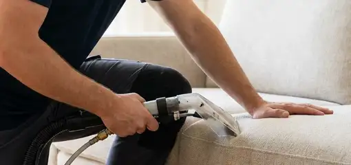 Professional upholstery cleaner deep-cleaning a fabric sofa with a handheld extraction tool, Orange, CA.